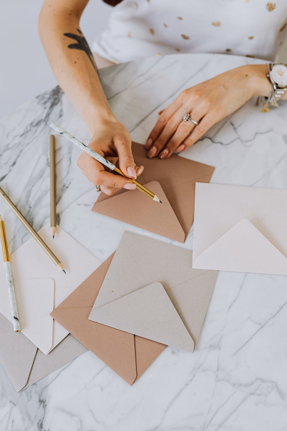 Mains écrivant au crayon sur une enveloppe kraft, parmi des cartes vierges