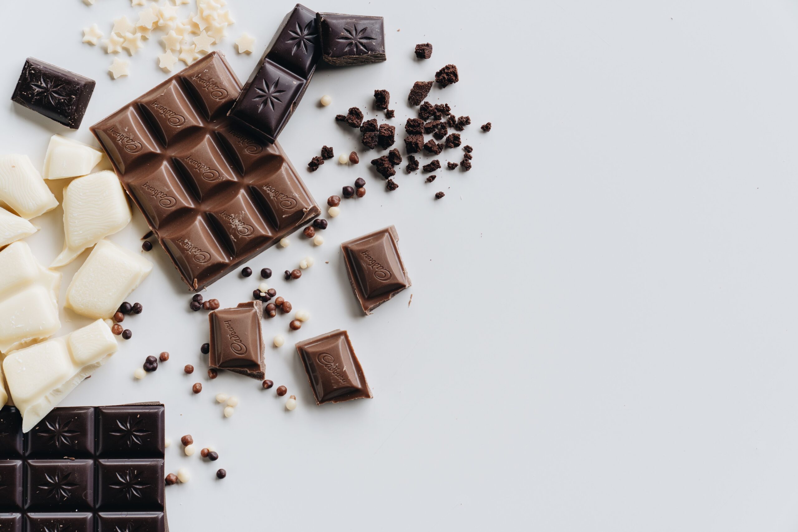 Morceaux de chocolat noir, au lait et blanc sur une table claire