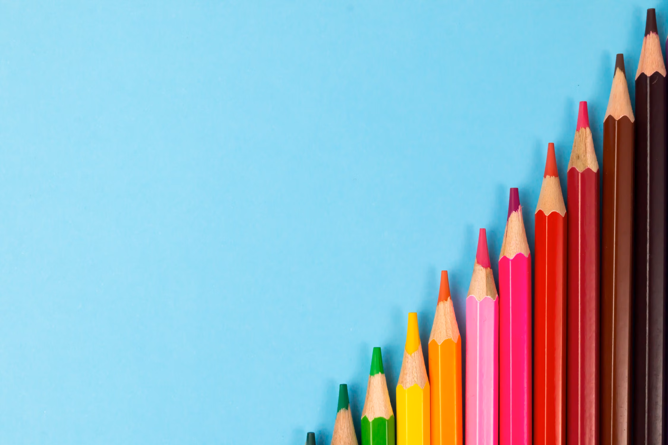 Crayons de couleur alignés sur un fond bleu turquoise
