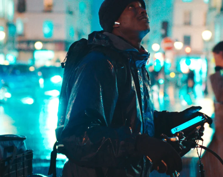 Souleymane avec son vélo de livraison dans une rue de Paris la nuit