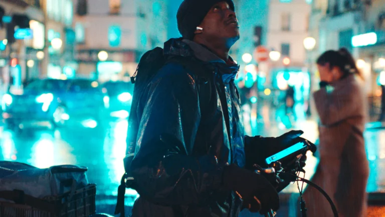 Souleymane avec son vélo de livraison dans une rue de Paris la nuit