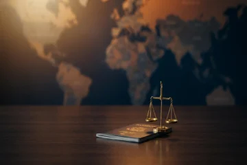 Passeport ouvert sur bureau sombre avec balance de justice et bouclier juridique sur fond bleu nuit et orange