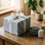 Cadeaux fête des pères tech : enceinte JBL, écouteurs sans fil et livre Kindle emballés sur une table en bois, lumière douce du matin
