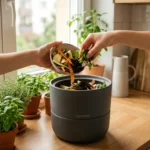 Mains ajoutant des epluchures dans un lombricomposteur moderne sur un plan de travail de cuisine eclaire