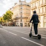 Trottinette électrique 2026 : jeune adulte en tenue moderne sur une trottinette urbaine dans un boulevard haussmannien parisien