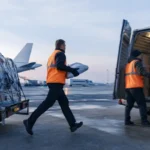 Coursier transférant rapidement un colis depuis le fret aérien vers une camionnette.