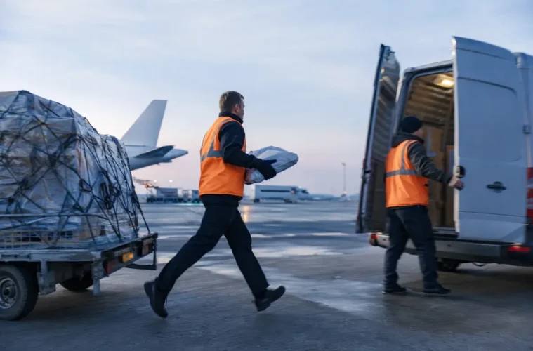 Coursier transférant rapidement un colis depuis le fret aérien vers une camionnette.