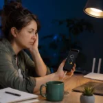 WhatsApp : pourquoi la sauvegarde ne peut-elle pas se terminer ? Femme attendant la fin d’une sauvegarde de téléphone bloquée dans son bureau.