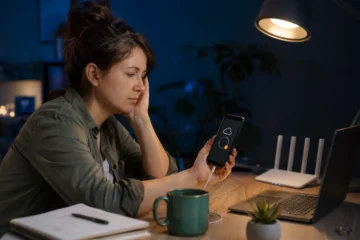 Femme attendant la fin d’une sauvegarde de téléphone bloquée dans son bureau.