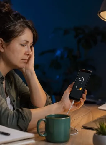 Femme attendant la fin d’une sauvegarde de téléphone bloquée dans son bureau.