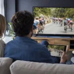 Un couple regarde une course cycliste sur une télévision et une tablette