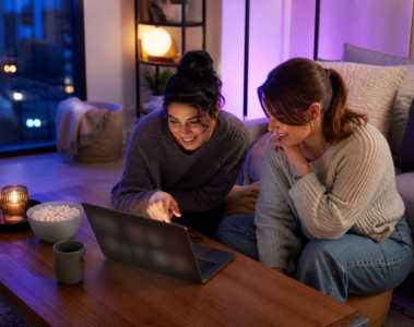 Deux jeunes femmes regardant du streaming sur un ordinateur portable dans un salon