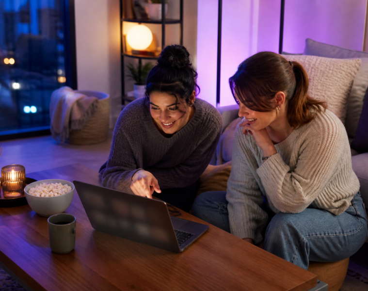 Deux jeunes femmes regardant du streaming sur un ordinateur portable dans un salon
