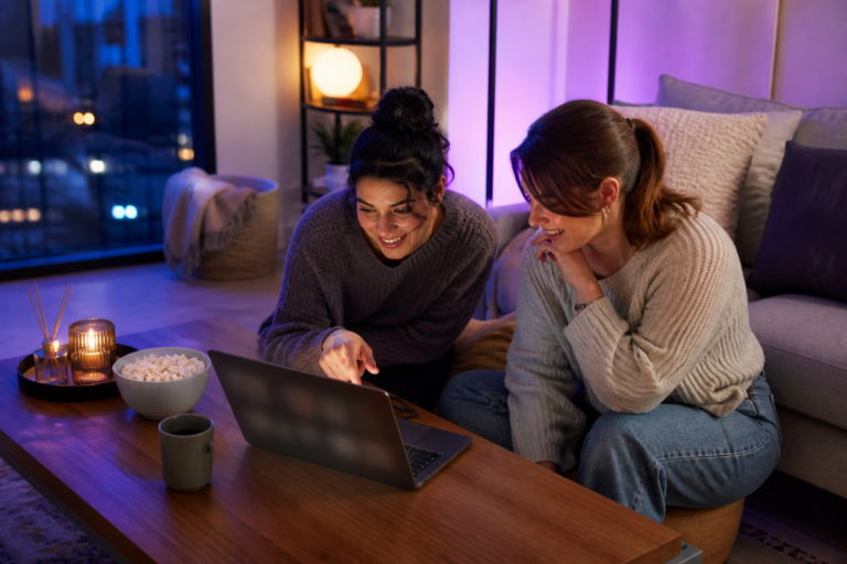 Deux jeunes femmes regardant du streaming sur un ordinateur portable dans un salon