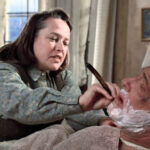 Misery : explication de la fin du film (1990) Annie Wilkes, incarnée par Kathy Bates, tient un rasoir près du visage de Paul Sheldon, allongé dans Misery (1990).