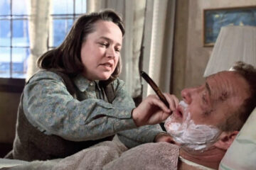 Annie Wilkes, incarnée par Kathy Bates, tient un rasoir près du visage de Paul Sheldon, allongé dans Misery (1990).