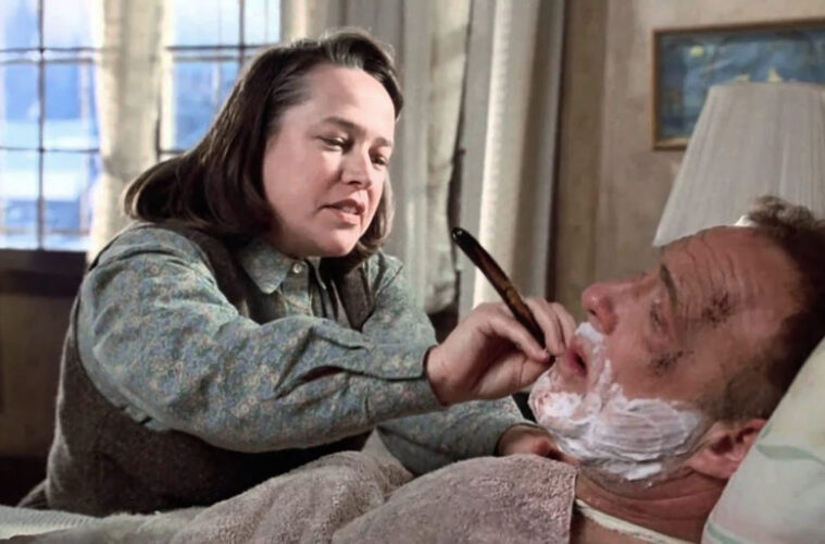 Annie Wilkes, incarnée par Kathy Bates, tient un rasoir près du visage de Paul Sheldon, allongé dans Misery (1990).