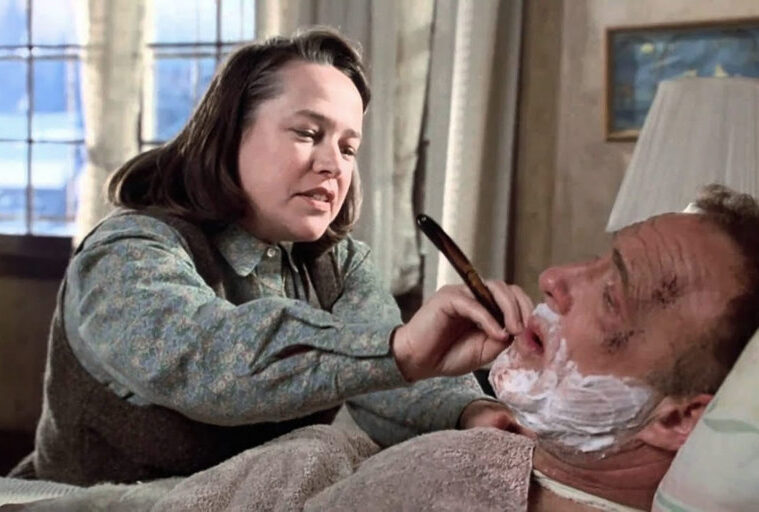 Annie Wilkes, incarnée par Kathy Bates, tient un rasoir près du visage de Paul Sheldon, allongé dans Misery (1990).