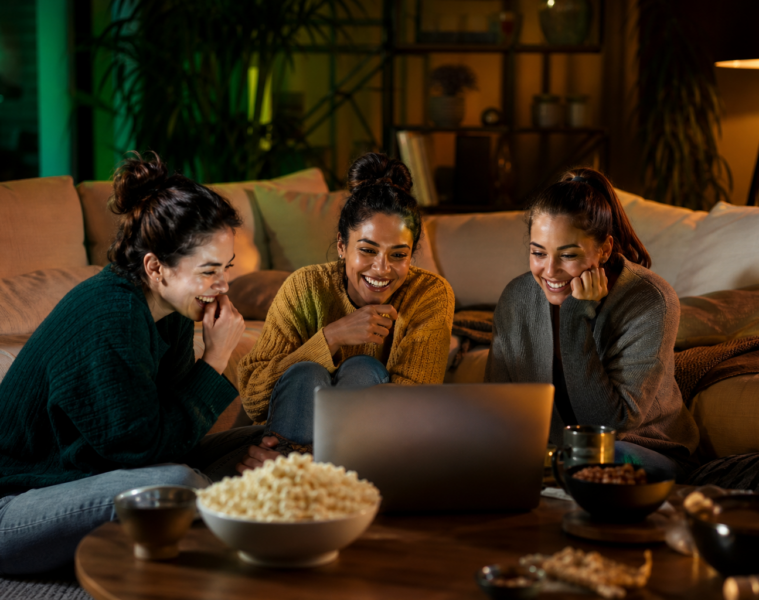 Trois jeunes femmes regardant du streaming ensemble sur un ordinateur portable