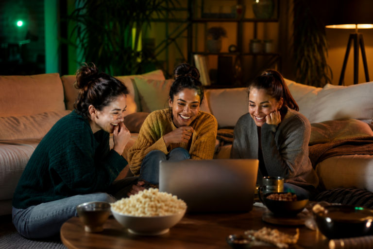 Trois jeunes femmes regardant du streaming ensemble sur un ordinateur portable