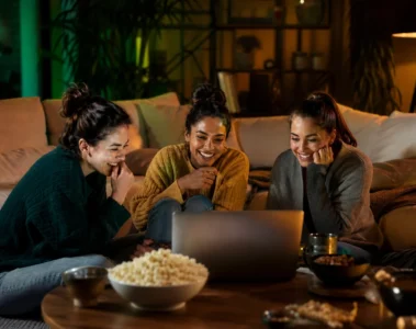Trois jeunes femmes regardant du streaming ensemble sur un ordinateur portable