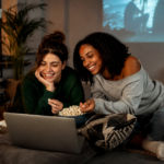 Vombam : nouvelle adresse et accès au site en septembre 2026 Deux jeunes femmes adultes regardant du streaming sur un ordinateur portable