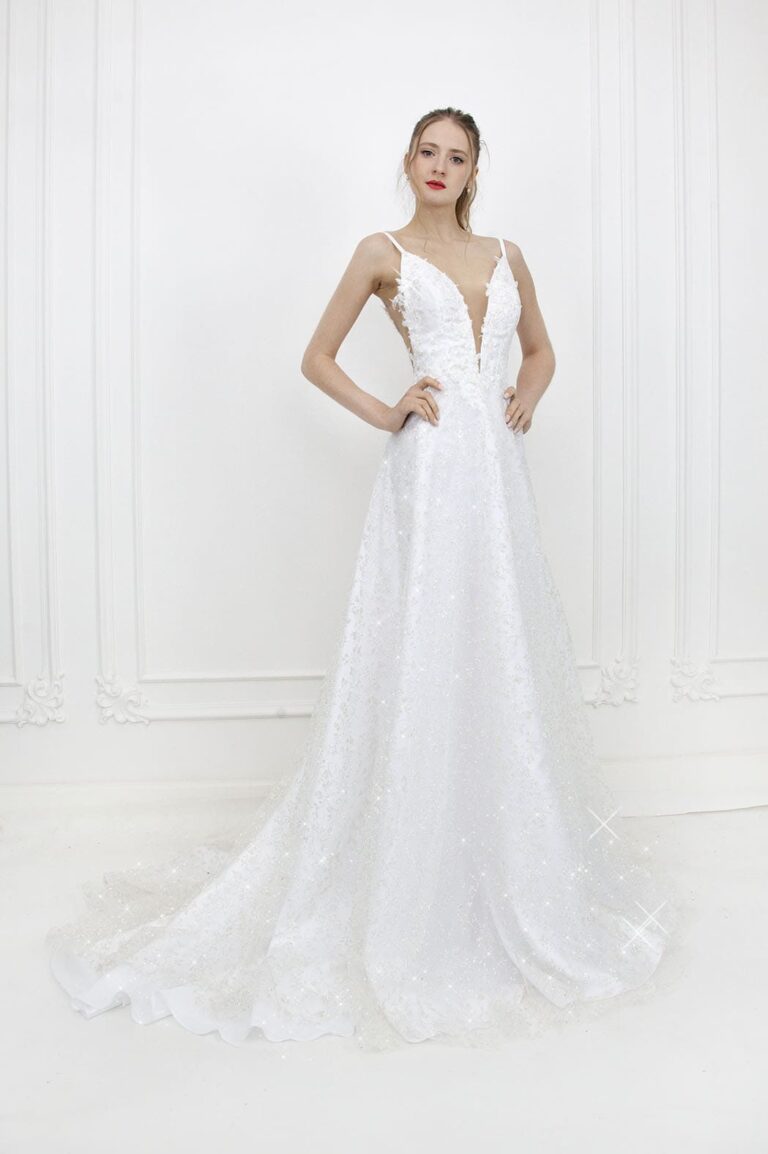 Modèle portant une robe de mariée blanche à fines bretelles et longue traîne