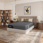 Matelas hybride Novilla AiryFlow gris installé sur un sommier dans une chambre aux tons beige et bois. Visuel produit fourni par Novilla dans le brief, page 3.